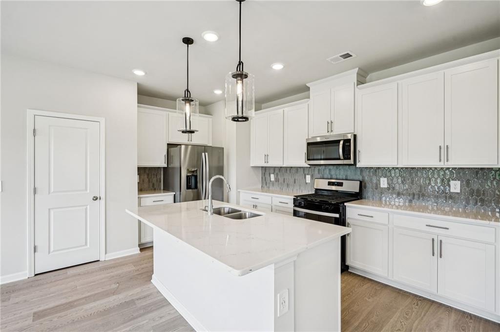 2034 Avalon Ridge Conyers, GA 30013 - Photo 12 of 35 a kitchen with white cabinets and stainless steel appliances