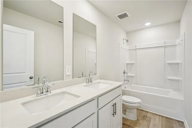 a bathroom with a bathtub shower sink vanity mirror and toilet