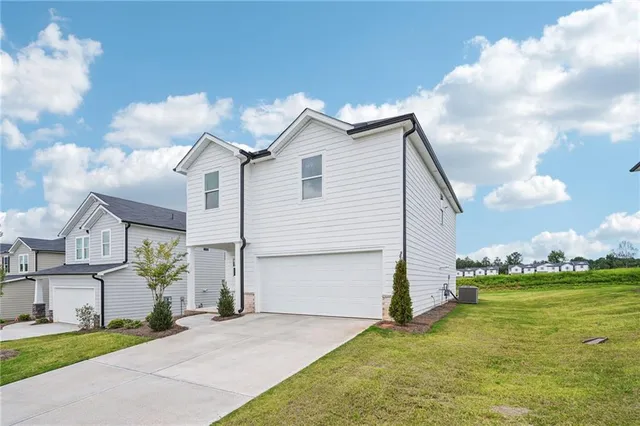 a view of a white house next to a yard with big trees