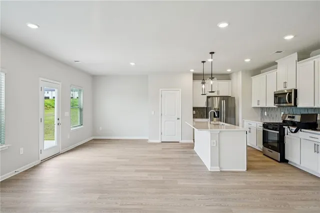 a view of kitchen with stainless steel appliances kitchen island hard wood floors and fireplace