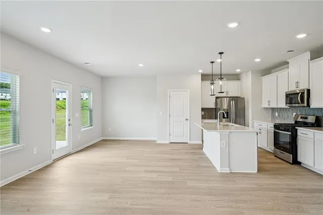 a large white kitchen with stainless steel appliances kitchen island granite countertop a large counter top and stainless steel appliances