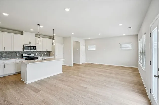 a large white kitchen with kitchen island a sink a stove a refrigerator and white cabinets
