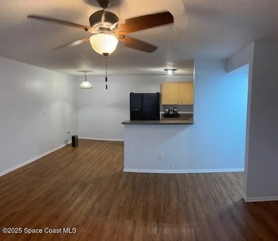 a view of empty room with wooden floor and ceiling fan