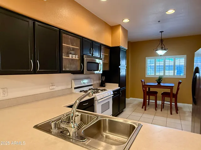 a kitchen with stainless steel appliances a stove a sink a microwave a dining table and chairs