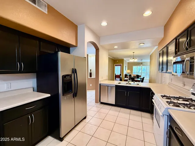 a kitchen with stainless steel appliances granite countertop a refrigerator a sink a stove top oven and cabinets