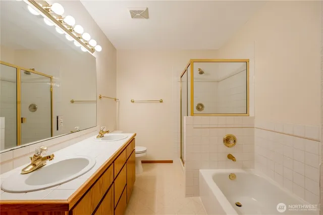 a bathroom with a tub sink double vanity and mirror