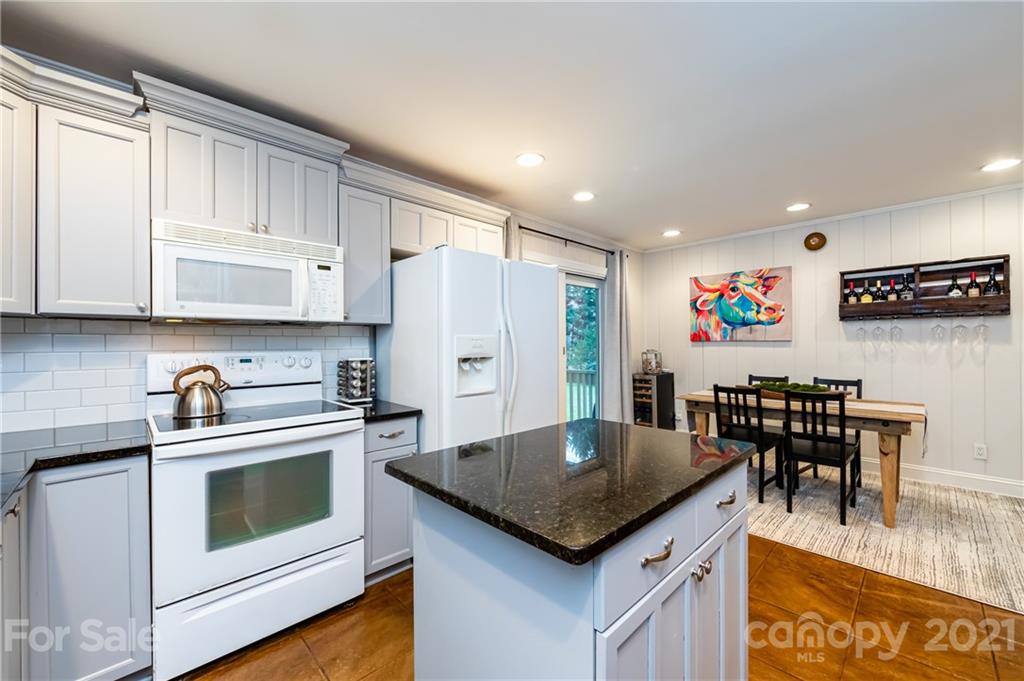 1417 Burnley Road Charlotte, NC 28210 - Photo 20 of 43 a kitchen with stainless steel appliances granite countertop a stove a refrigerator a microwave a dining table and chairs with wooden floor