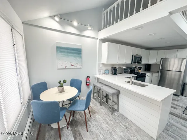 a kitchen with stainless steel appliances kitchen island granite countertop a sink a stove a refrigerator and island with wooden floor