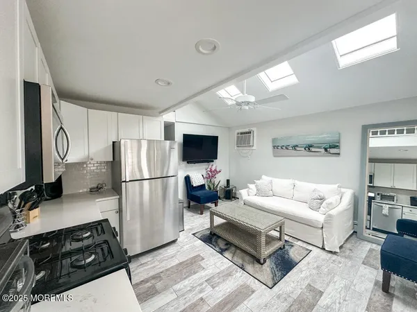 a living room with furniture a flat screen tv and a refrigerator