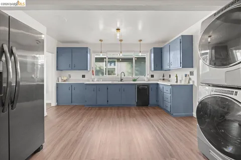 a kitchen with stainless steel appliances granite countertop a refrigerator a sink dishwasher a stove with wooden cabinets and floors