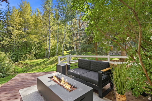 1462 Rio Grande Road Park City, UT 84098 - Photo 25 of 30 Expansive wood-finish decking with an integrated fire feature, set against a backdrop of mature trees and a sloped lawn