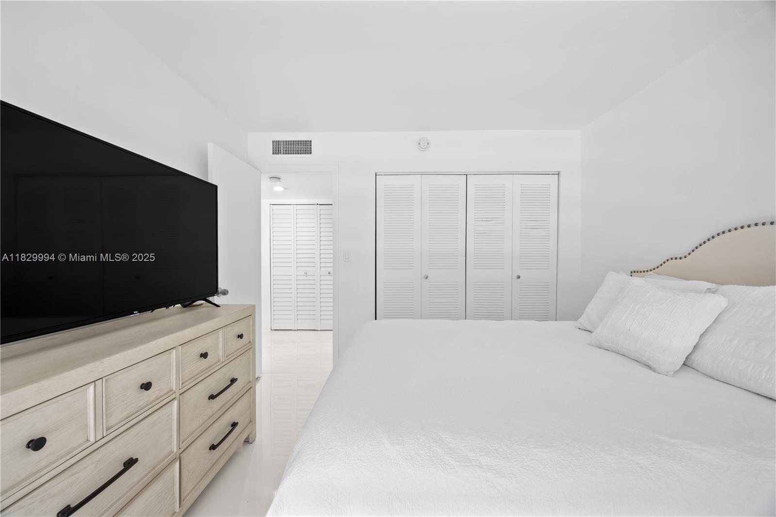8810 Southwest 132nd Place, Unit 101DN Miami, FL 33186 - Photo 18 of 39 a bedroom with a bed and a flat screen tv