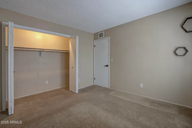 a view of an empty room with closet and a window