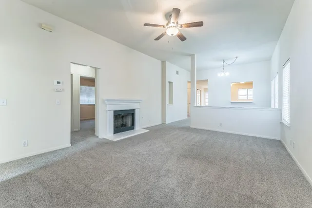 an empty room with a fireplace and a ceiling fan
