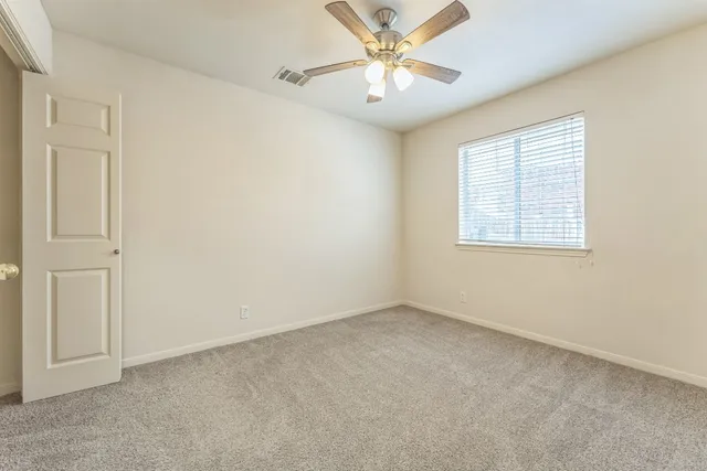 an empty room with a window and a fan