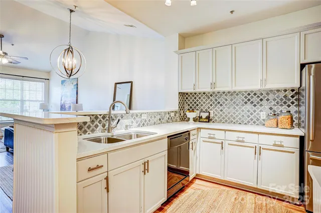 a kitchen with a sink dishwasher and white cabinets with wooden floor