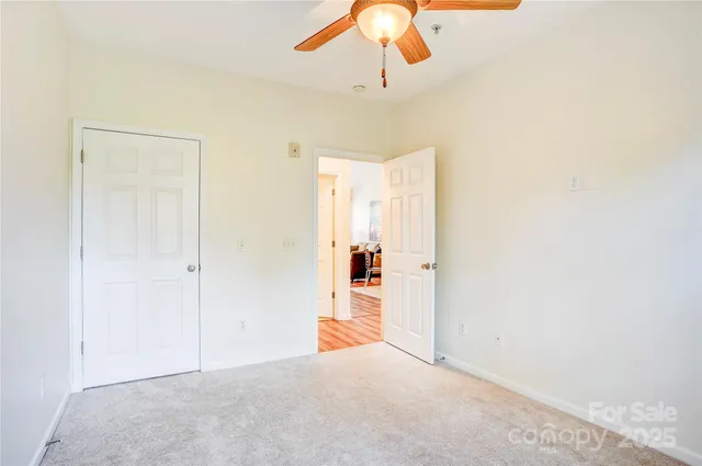 an empty room with a chandelier fan and wooden floor