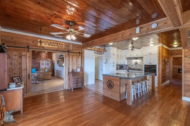 a large kitchen with stainless steel appliances granite countertop a large counter top and a wooden floors