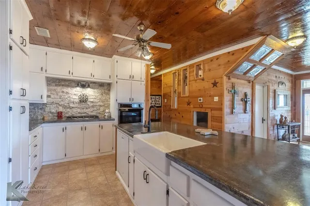 a kitchen with stainless steel appliances granite countertop a sink dishwasher and white cabinets with wooden floor