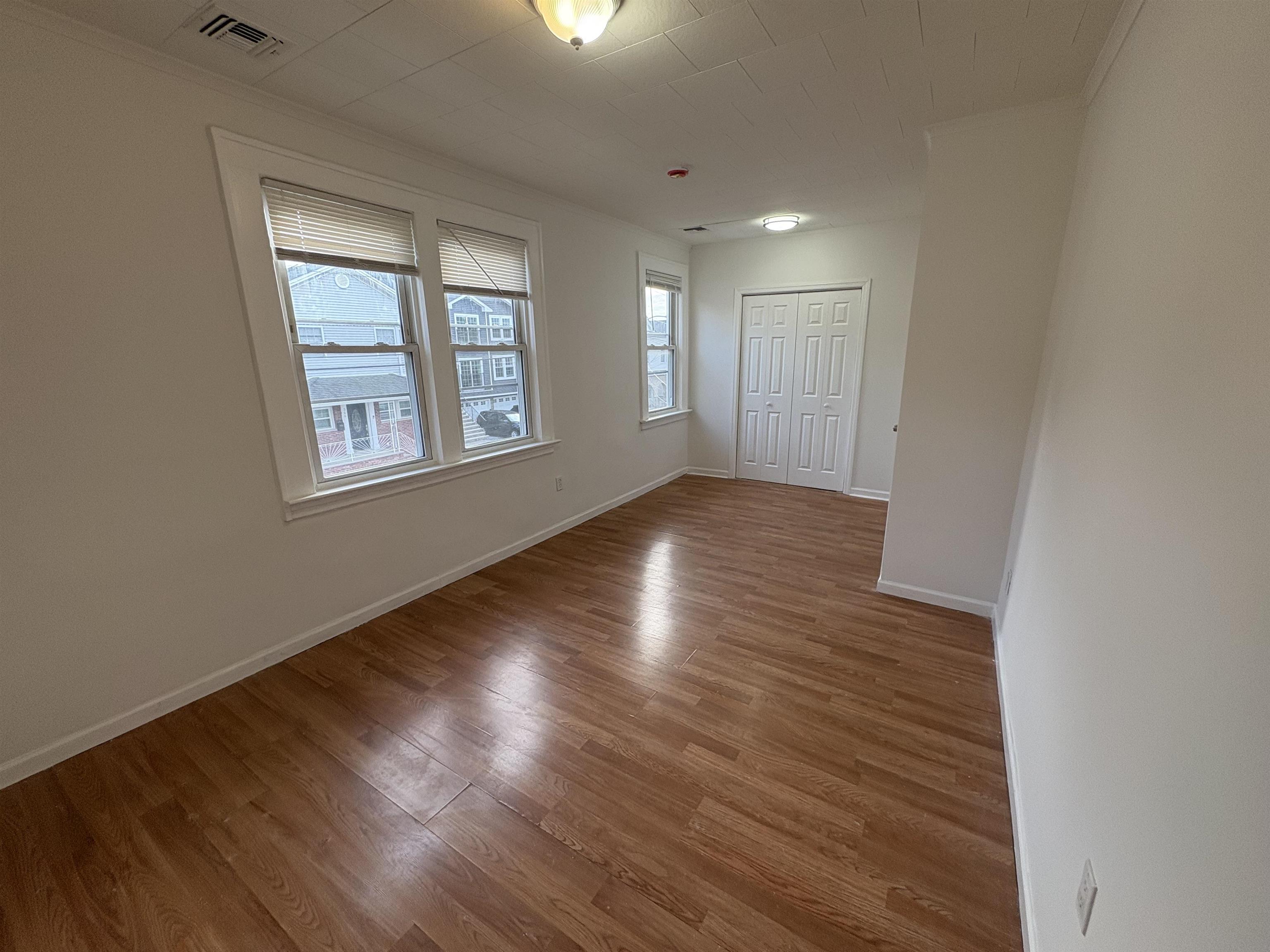 355 Princeton Avenue, Unit 2 Hillside, NJ 07205 - Photo 9 of 11 an empty room with wooden floor and windows