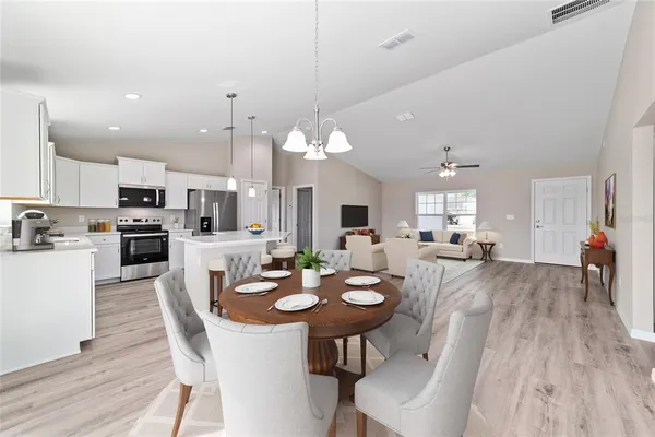 a view of a dining room and livingroom with furniture wooden floor kitchen view