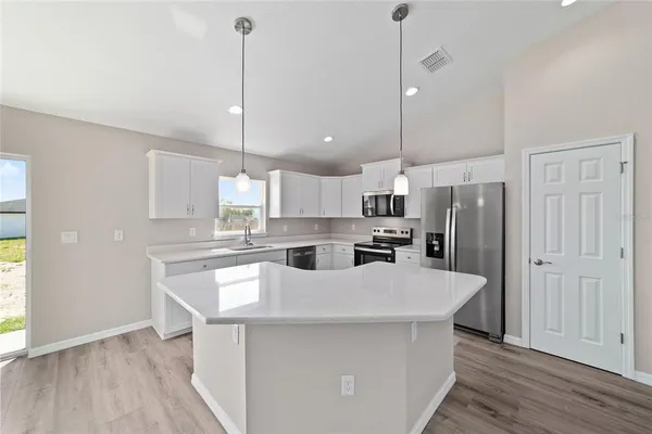 a kitchen with kitchen island a sink a center island a stove and a wooden floor