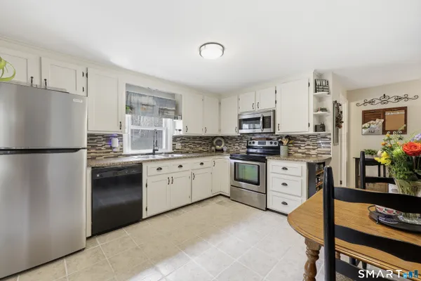 a kitchen with granite countertop a refrigerator stove top oven and sink