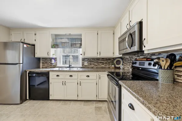 a kitchen with stainless steel appliances granite countertop a stove a sink and a refrigerator