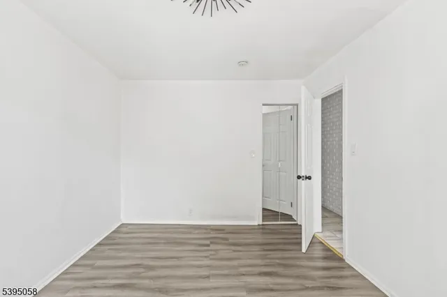 a view of an empty room with wooden floor and a bathroom