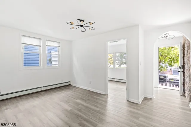 an empty room with wooden floor a ceiling fan and windows