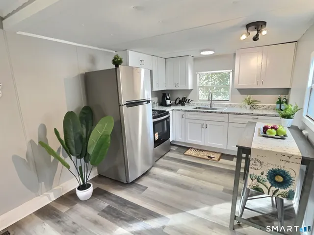 a kitchen with stainless steel appliances a refrigerator a stove a sink a dining table and chairs