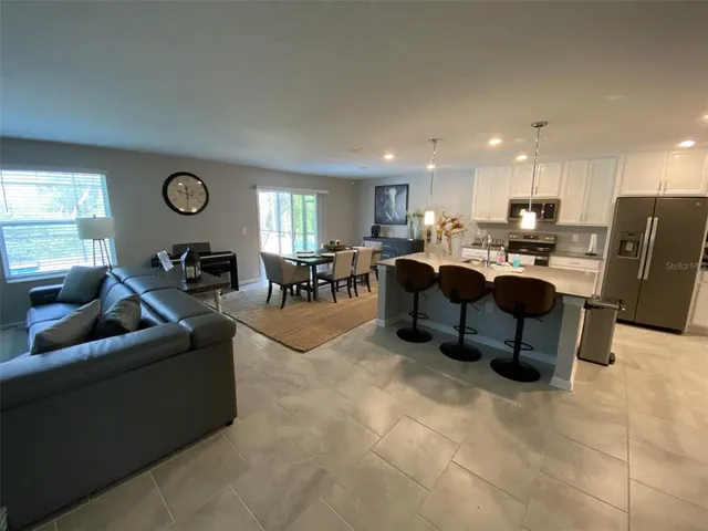 a living room with furniture kitchen view and a wooden floor