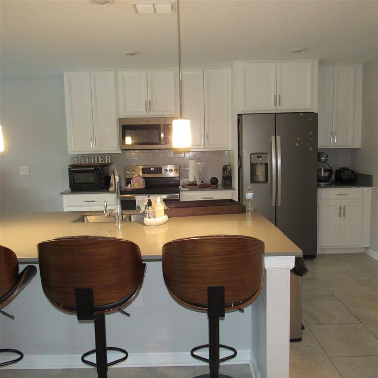 5686 Alenlon Way Mount Dora, FL 32757 - Photo 14 of 62 a kitchen with stainless steel appliances a stove a refrigerator a sink a counter space and cabinets