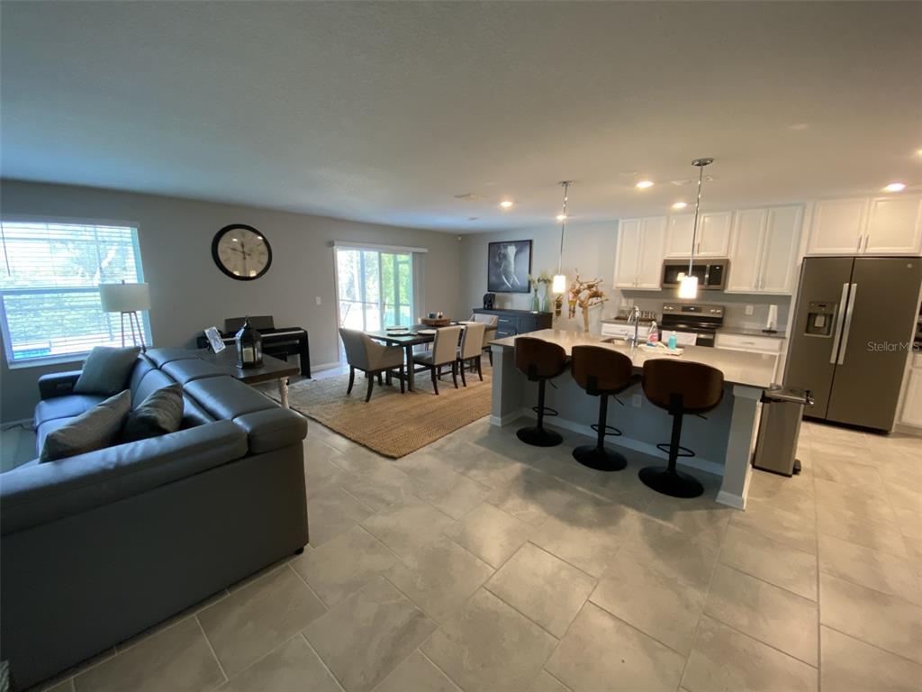 5686 Alenlon Way Mount Dora, FL 32757 - Photo 10 of 62 a living room with furniture a table and kitchen view
