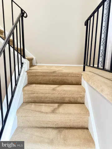 a view of staircase with white walls and a rug