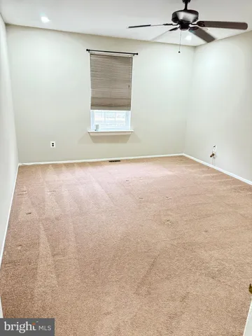 an empty room with a ceiling fan and windows