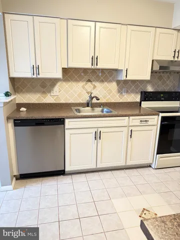 a kitchen with granite countertop a sink a stove and white cabinets