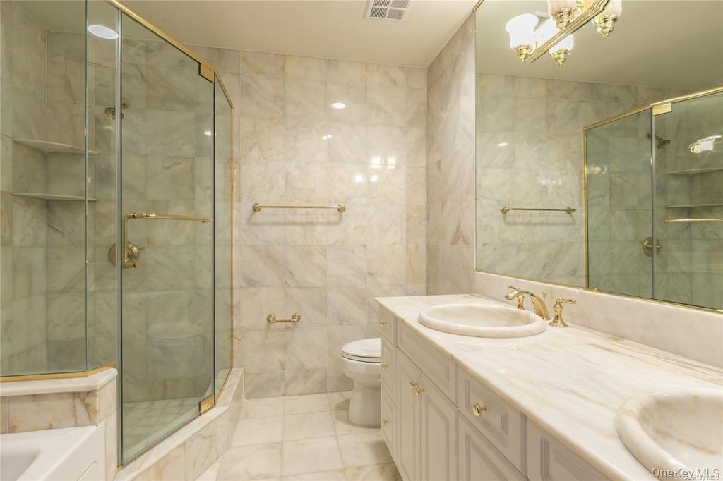 171 Great Neck Road, Unit 1N Great Neck, NY 11021 - Photo 13 of 15 Bathroom with double vanity, tile walls, a stall shower, and a tub
