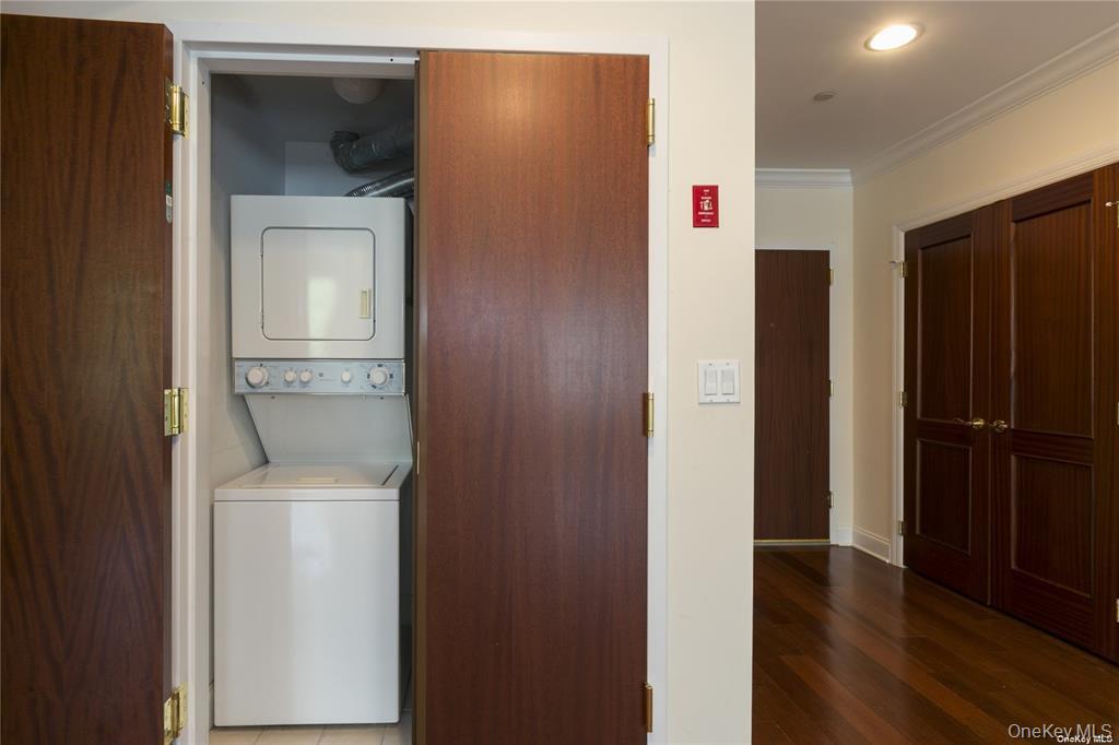 171 Great Neck Road, Unit 1N Great Neck, NY 11021 - Photo 8 of 15 Laundry area with crown molding, stacked washer / dryer, dark wood-style flooring, and recessed lighting