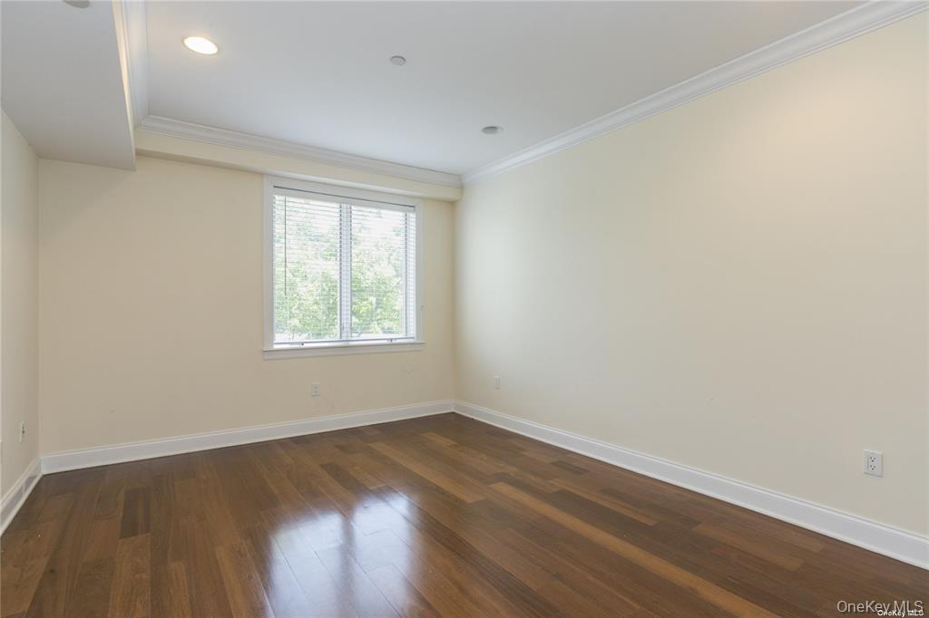 171 Great Neck Road, Unit 1N Great Neck, NY 11021 - Photo 10 of 15 Empty room with ornamental molding and dark wood-style floors