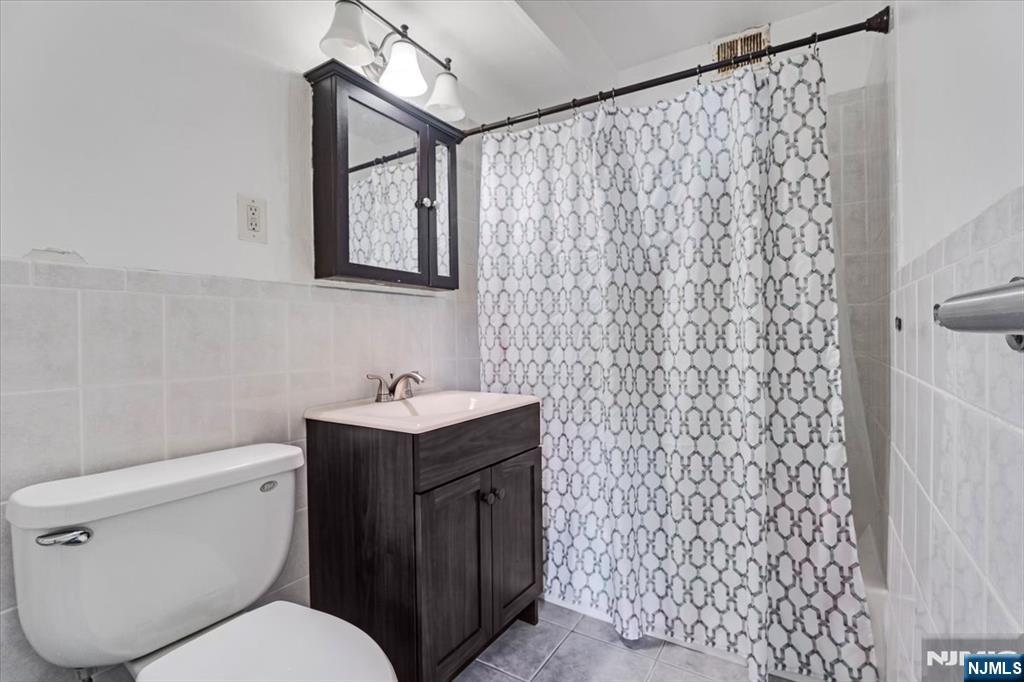90 Prospect Avenue, Unit 7A Hackensack, NJ 07601 - Photo 6 of 21 a bathroom with a toilet sink vanity and mirror