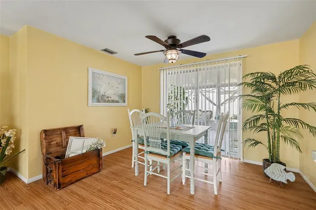 a dining room with wooden floor a chandelier fan a glass table and chairs