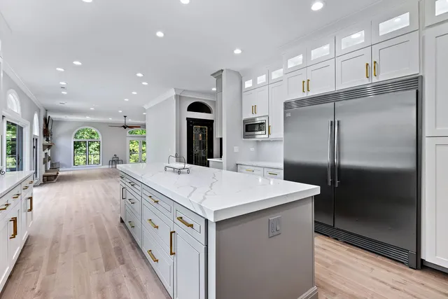 a large kitchen with stainless steel appliances granite countertop a large center island a stove a refrigerator and a cabinets