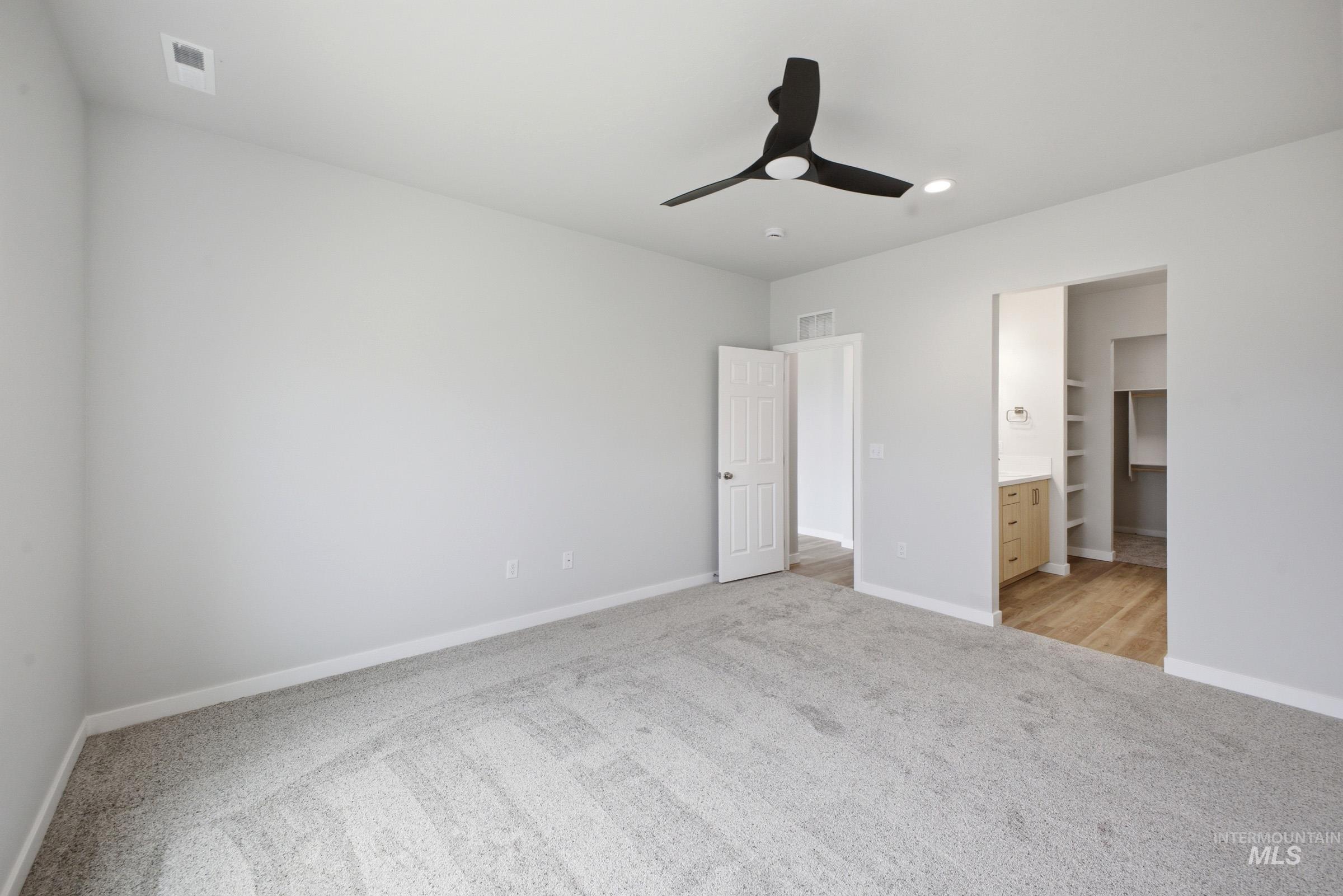 14104 Shiny Spruce Street Caldwell, ID 83607 - Photo 15 of 20 Spacious room featuring light gray carpeting and walls, a modern black ceiling fan with integrated lighting, and white baseboards
