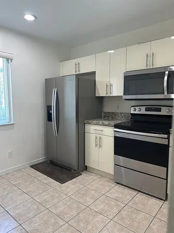 a kitchen with granite countertop a refrigerator stove and microwave