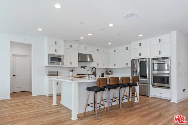 a kitchen with stainless steel appliances kitchen island granite countertop a refrigerator and a stove top oven