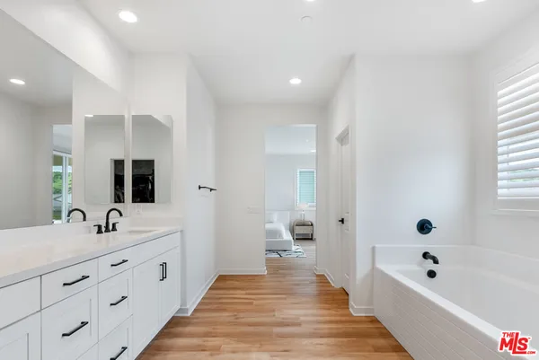 a spacious bathroom with a double vanity sink a mirror and a bathtub
