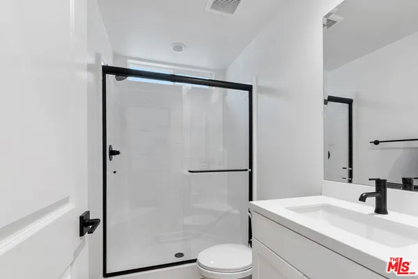 a bathroom with a shower sink vanity mirror and toilet
