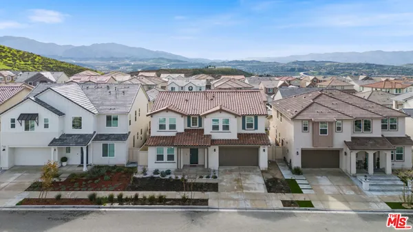 a front view of residential houses with yard and mountain view in back