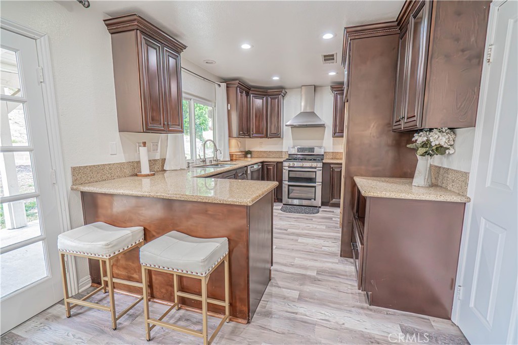 25535 Chisom Lane Stevenson Ranch, CA 91381 - Photo 13 of 37 a kitchen with kitchen island granite countertop wooden cabinets and stainless steel appliances